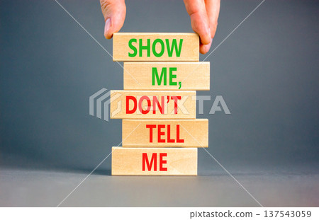 Tell or show symbol. Concept words Show me, do not tell me on beautiful wooden blocks. Beautiful grey paper background. Businessman hand. Business tell or show concept. Copy space. 137543059