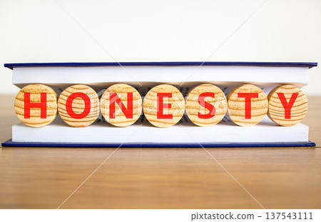Honesty word symbol. Concept word Honesty on beautiful wooden circles in book. Beautiful wooden table white background. Business honesty concept. Copy space. 137543111