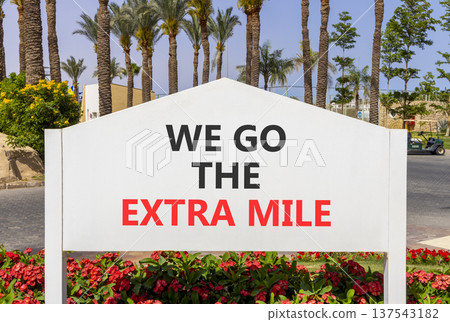 Support, help we go the extra mile symbol. Concept words We go the extra mile on beautiful white road sign. Beautiful palm trees blue sky background. Business we go the extra mile concept. Copy space. Support, help we go the extra mile symbol. Concept words We go the extra mile on beautiful white road sign. Beautiful palm trees blue sky background. Business we go the extra mile concept. Copy space. 137543182