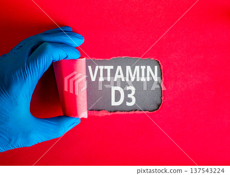 Vitamin D3 symbol. Concept words Vitamin D3 on beautiful grey paper. Doctor hand in blue medical glove. Beautiful red background. Medical healthy lifestyle Vitamin D3 concept. Vitamin D3 symbol. Concept words Vitamin D3 on beautiful grey paper. Doctor hand in blue medical glove. Beautiful red background. Medical healthy lifestyle Vitamin D3 concept. 137543224