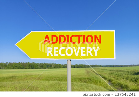 Addiction recovery symbol. Concept words Addiction recovery on beautiful yellow road sign. Beautiful blue sky green grass field background. Psychology addiction recovery concept. Copy space. 137543241