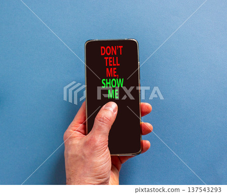 Tell or show symbol. Concept words Do not tell me, show me on beautiful phone screen. Beautiful blue background. Businessman hand. Business tell or show concept. Copy space. Tell or show symbol. Concept words Do not tell me, show me on beautiful phone screen. Beautiful blue background. Businessman hand. Business tell or show concept. Copy space. 137543293
