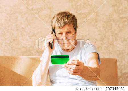 A naive elderly woman gives her bank card details to telephone scammers. Financial fraud using personal information, manipulation, criminal activity 137543411
