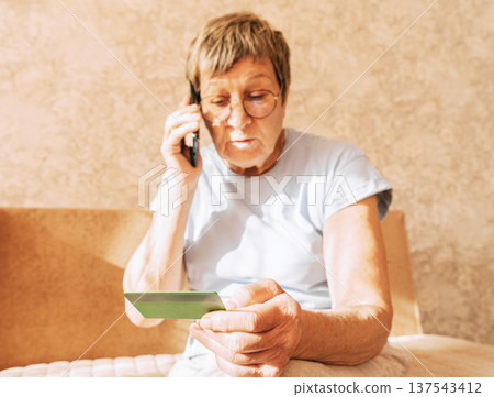 A naive elderly woman gives her bank card details to telephone scammers. Financial fraud using personal information, manipulation, criminal activity 137543412
