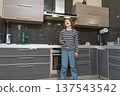 Laughing boy holding a smartphone in a modern kitchen. Happy child having fun with mobile device 137543542