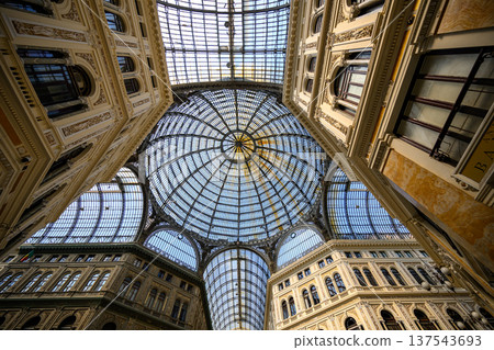 Galleria Umberto I in Naples, Italy, features an ornate glass dome ceiling supported by intricate wrought iron framework. The architectural design is rich with classical details. Galleria Umberto I in Naples, Italy, features an ornate glass dome ceiling supported by intricate wrought iron framework. The architectural design is rich with classical details. 137543693