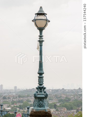 A commanding, ornate Victorian lamppost stands as the central focus of the image, its aged teal patina suggesting a rich history. A commanding, ornate Victorian lamppost stands as the central focus of the image, its aged teal patina suggesting a rich history. 137544240