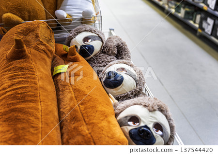 Group of smiling sloth plush toys on a wire shelf in a toy store. Group of smiling sloth plush toys on a wire shelf in a toy store. 137544420