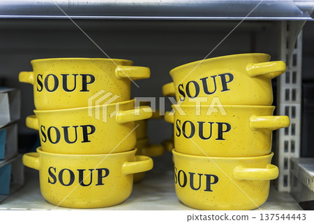 Yellow ceramic soup bowls with handles on a retail store shelf. Yellow ceramic soup bowls with handles on a retail store shelf. 137544443