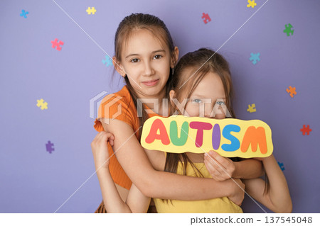 Happy children show a colorful inscription on a card with the word autism, demonstrating support and love for people with autism spectrum disorder. 137545048