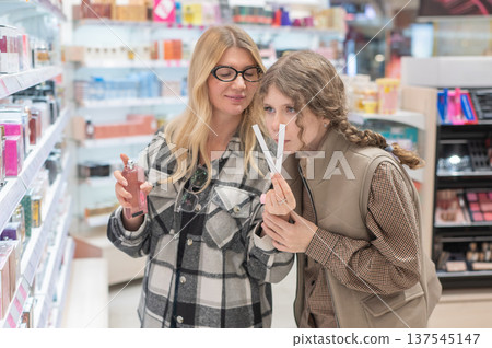 A mother and her teenage daughter are shopping for cosmetics. A mother and her teenage daughter are shopping for cosmetics. 137545147