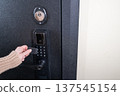 A woman opens a modern smart door lock using a contactless key. 137545154