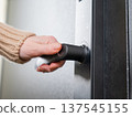 A woman opens a modern smart door lock with a digital keypad and biometric fingerprint access. 137545155