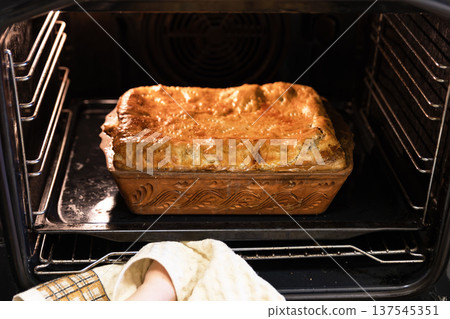Freshly baked golden brown pie in a ceramic dish inside the oven. 137545351