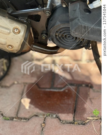 Motorcycle oil leak on paved ground highlighting mechanical maintenance issues 137545844