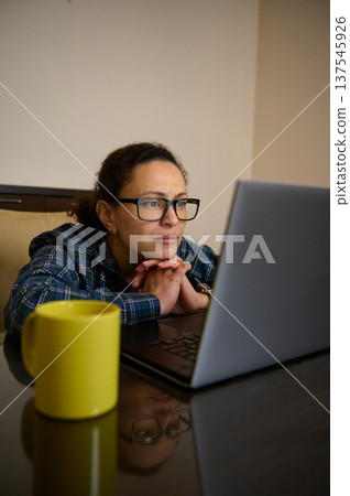 Woman Entrepreneur Working From Home On Laptop Telecommuting Remotely With Coffee Cup Woman Entrepreneur Working From Home On Laptop Telecommuting Remotely With Coffee Cup 137545926