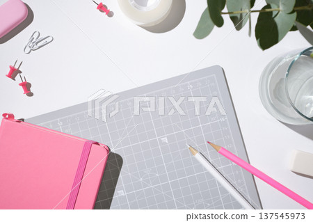 Flat lay of pink office supplies, a closed notebook on a grey cutting mat. Minimalist workspace for creative planning. Copyspace. Flat lay of pink office supplies, a closed notebook on a grey cutting mat. Minimalist workspace for creative planning. Copyspace. 137545973