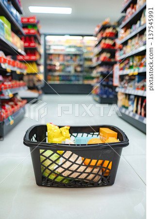 Shopping basket filled with groceries in supermarket aisle 137545991