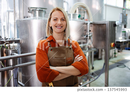 Woman brewmaster standing in craft beer brewery with arms crossed 137545993