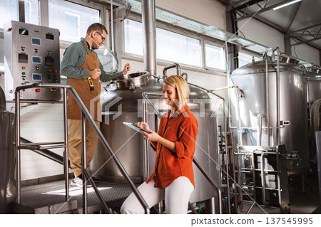 Brewery workers monitoring beer brewing process using tablet Brewery workers monitoring beer brewing process using tablet 137545995
