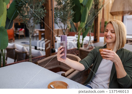 Woman enjoying coffee and taking selfie at cafe Woman enjoying coffee and taking selfie at cafe 137546013