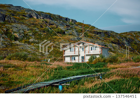 A houses stands on the coast of the Barents Sea at sunny weather, Teriberka, Russia, the rocky shore with colourful arctic carpet of moss, yagel, Tundra at autumn, Murmansk region A houses stands on the coast of the Barents Sea at sunny weather, Teriberka, Russia, the rocky shore with colourful arctic carpet of moss, yagel, Tundra at autumn, Murmansk region 137546451