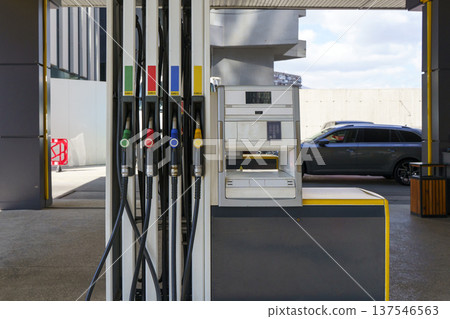 Fuel pump nozzles hanging at a modern gas station during a period of high oil prices. A conceptual photography showcasing the global energy crisis, increasing gasoline costs 137546563