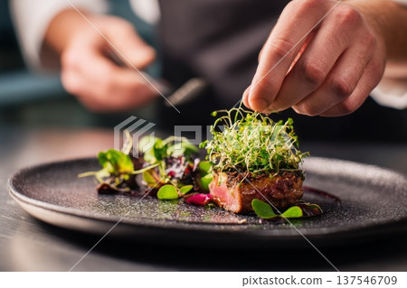 Chef Plates Gourmet Vegan Dish With Microgreens in High End Restaurant Kitchen Setting 137546709