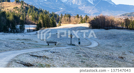 Curving alpine hiking trail across frosty meadow landscape in the Bavarian Alps Germany Curving alpine hiking trail across frosty meadow landscape in the Bavarian Alps Germany 137547043