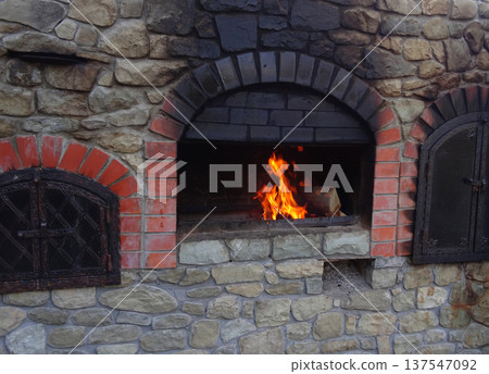 Fire burns in wood stove with soot on stones over fireplace   137547092