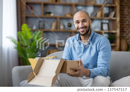 Happy man receiving new package, opening cardboard box and feeling excited about his delivery, enjoying positive customer experience from purchasing goods online 137547317