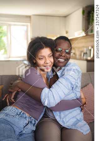 Two young women are hugging on the sofa at home Two young women are hugging on the sofa at home 137547324