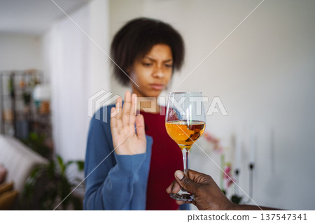 Young woman refusing a glass of wine with a serious face expression Young woman refusing a glass of wine with a serious face expression 137547341