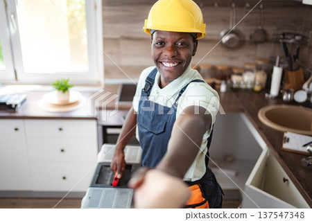 Smiling african american female worker shaking hands in kitchen during home renovation Smiling african american female worker shaking hands in kitchen during home renovation 137547348