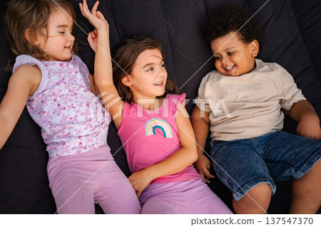 Diverse children smiling playing lying together on dark background 137547370