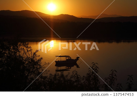 Small fishing boat with reflection in calm sea at sunrise. Small fishing boat with reflection in calm sea at sunrise. 137547453