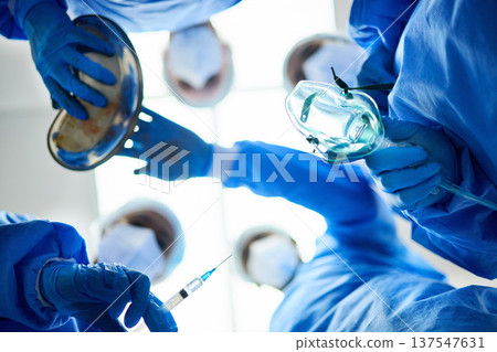 Surgery team, below and a doctors in a hospital or theatre to start operation with anesthesia. Surgeon, assistant and medical group together for emergency healthcare with a oxygen mask and syringe Surgery team, below and a doctors in a hospital or theatre to start operation with anesthesia. Surgeon, assistant and medical group together for emergency healthcare with a oxygen mask and syringe 137547631