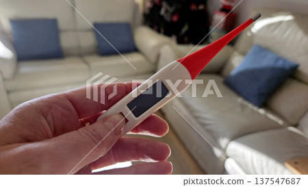 Digital thermometer in hand indoors for health and wellness Digital thermometer in hand indoors for health and wellness 137547687