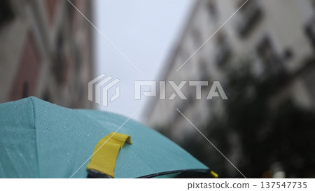 Urban rainy day scene with teal umbrella and city buildings. Horizontal banner. Copy space Urban rainy day scene with teal umbrella and city buildings. Horizontal banner. Copy space 137547735