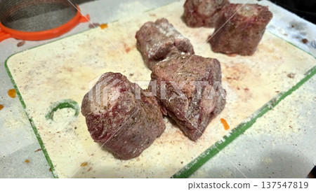 Preparing seasoned oxtail chunks for cooking in a rustic kitchen setting. Traditional Spanish dish. Typical food of Spain Preparing seasoned oxtail chunks for cooking in a rustic kitchen setting. Traditional Spanish dish. Typical food of Spain 137547819