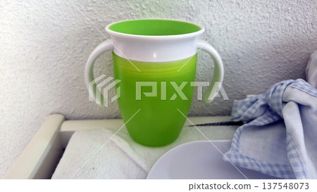 Colorful children's sippy cup with handles for easy gripping on table with soft fabric Colorful children's sippy cup with handles for easy gripping on table with soft fabric 137548073