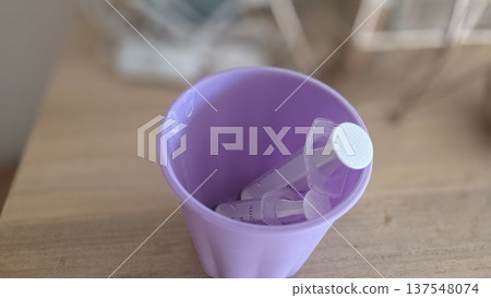 Purple cup with syringes on wooden surface for pediatric care and childhood health themes Purple cup with syringes on wooden surface for pediatric care and childhood health themes 137548074