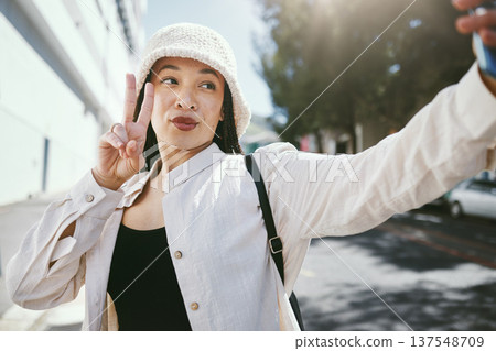 Woman on city street with selfie, peace sign and travel holiday memory or social media in streetwear. Influencer, streamer or gen z girl with urban fashion, photography and content creation for blog. Woman on city street with selfie, peace sign and travel holiday memory or social media in streetwear. Influencer, streamer or gen z girl with urban fashion, photography and content creation for blog. 137548709