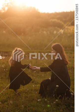 Mother And Daughter Dance By Water. Golden Hour Dance Of Mother And Child By Reflective Pond 137548945