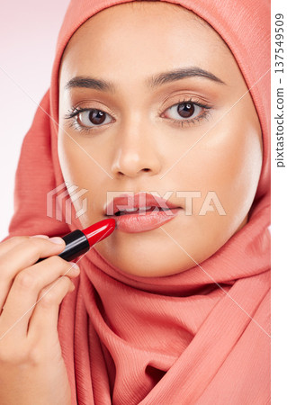 Portrait, beauty and makeup with a muslim woman closeup in studio on a pink background for cosmetics. Face, lipstick and islamic with a young model in an hijab to apply a product for red color 137549509