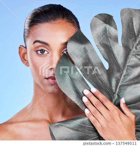 Natural beauty, woman and face, monstera leaf and glow with wellness and eco friendly dermatology on blue background. Sustainable skincare, green with collagen and cosmetics in portrait in studio 137549511