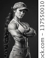 Strong bodybuilder woman posing confidently at a competition venue in black and white setting 137550010