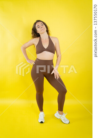 Confident woman posing in brown activewear during workout session Confident woman posing in brown activewear during workout session 137550170