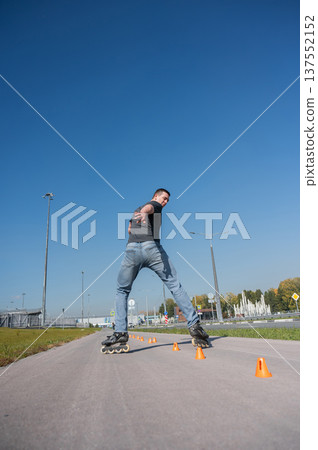 A Caucasian man rollerblades around the slalom course. 137552152