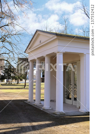 A white classical portico with columns in a park on a sunny day. Entrance to a pavilion or gallery. A white classical portico with columns in a park on a sunny day. Entrance to a pavilion or gallery. 137552412